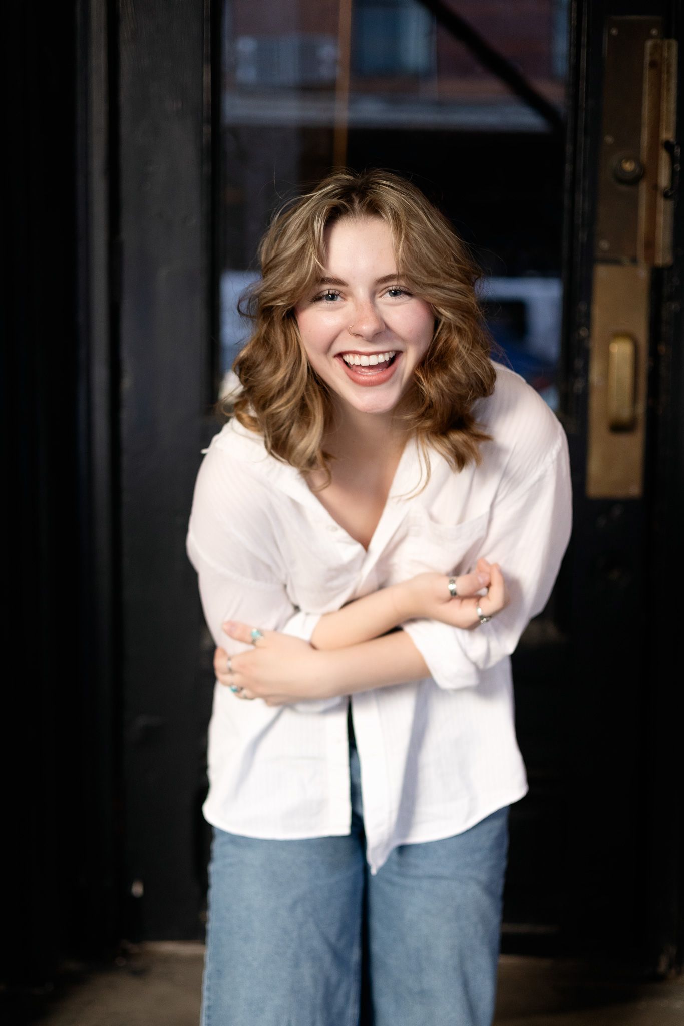 A series of portraits showing someone wearing a white shirt and jeans while leaning forward and smiling against a dark background.