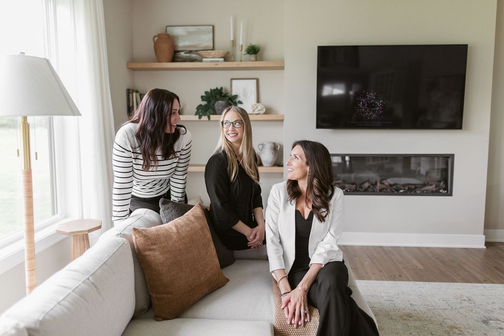 Two people relax together in a bright modern living room with floating shelves and white walls.