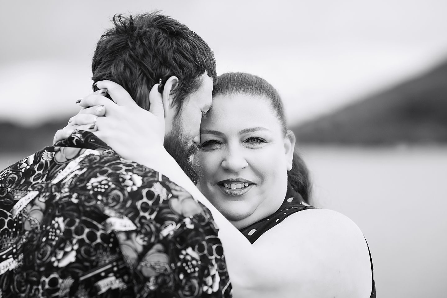 A black and white joyful wedding portrait showing the couple embracing in an intimate close-up moment.