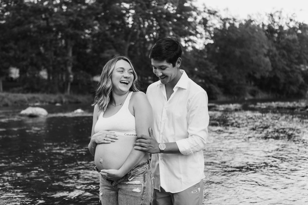 A couple shares tender moments by a lake during a romantic black and white outdoor photo session.