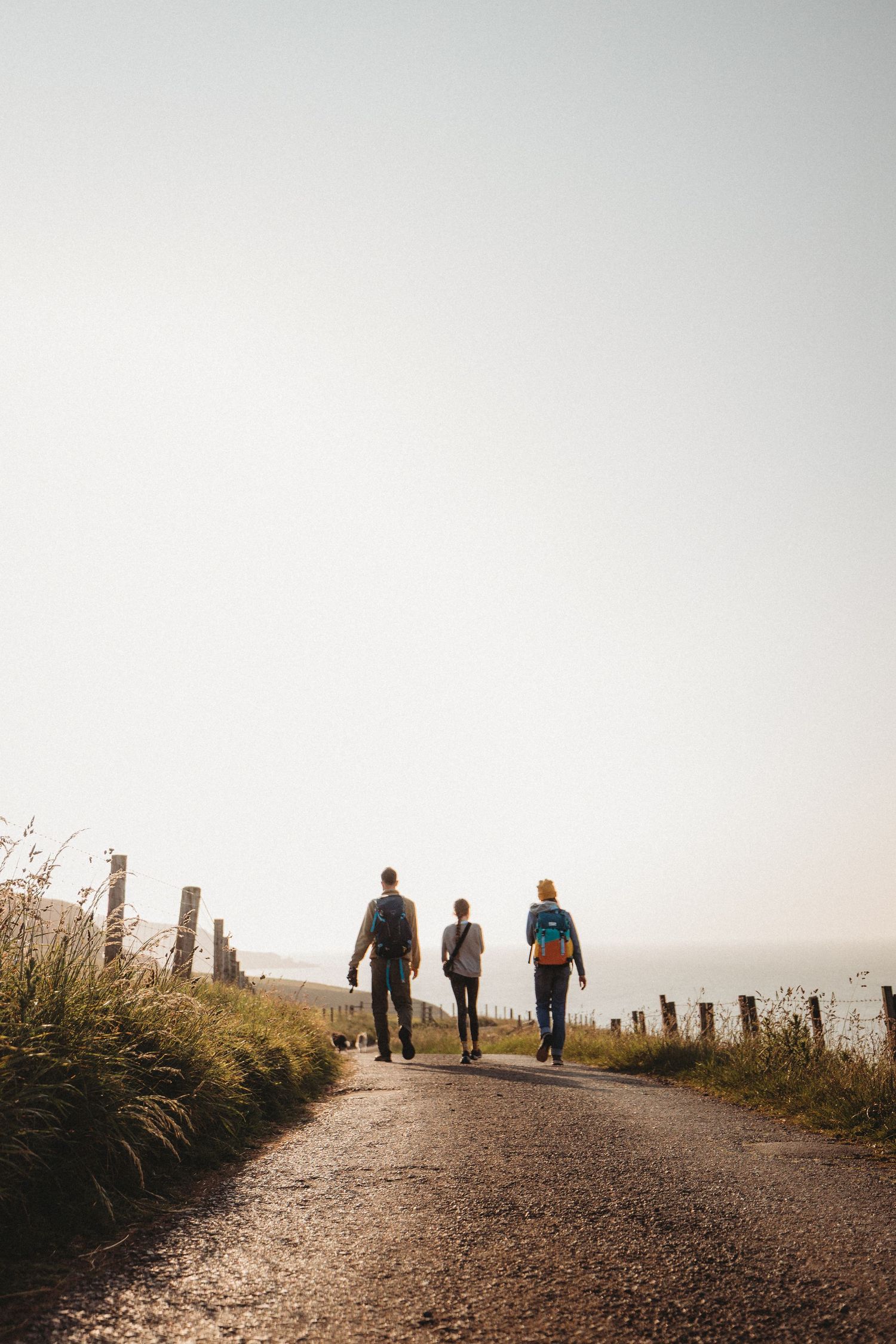 Silhouette stands with outstretched arms on foggy mountain path overlooking dramatic coastal landscape.