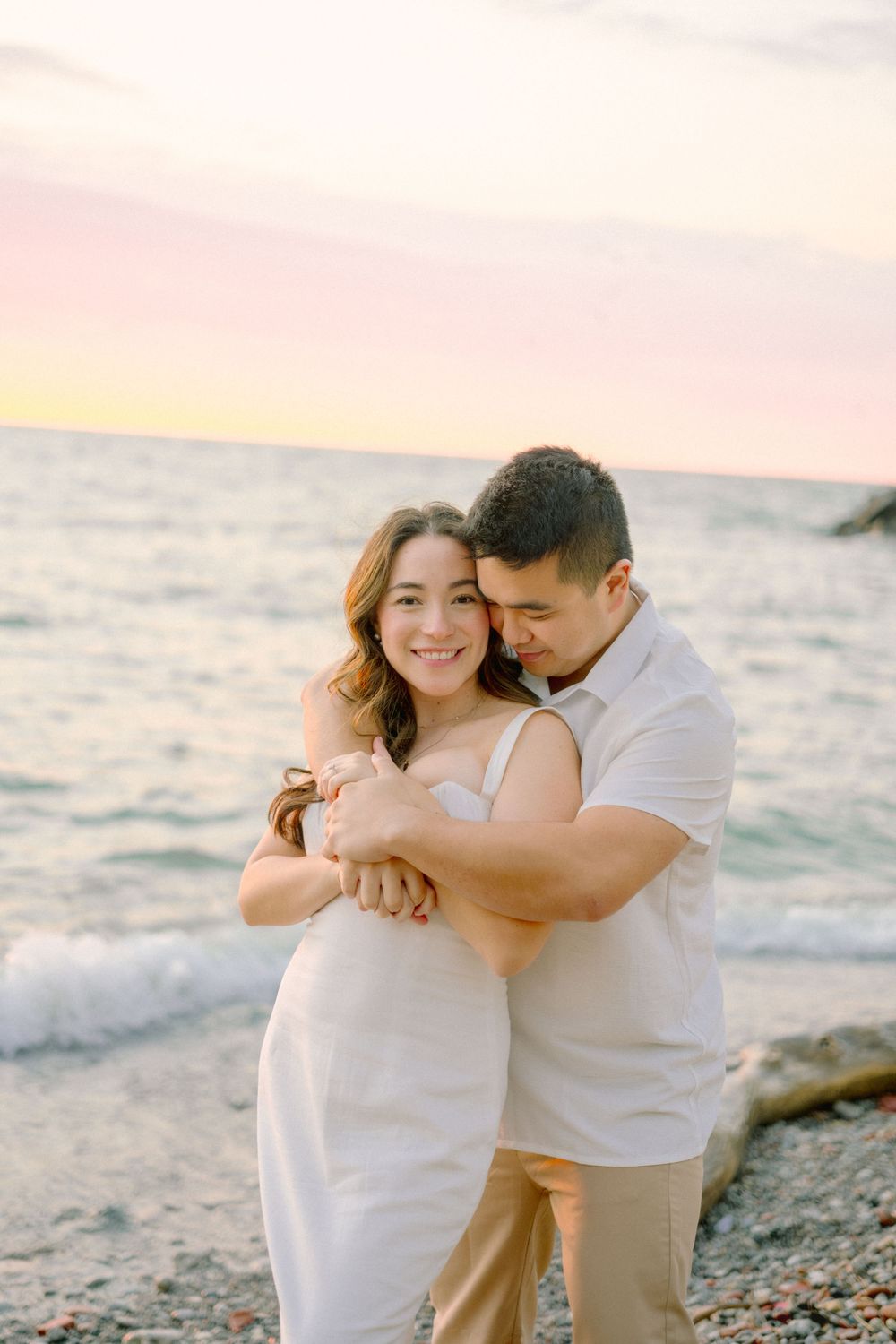 A tender moment captured on a rocky beach during sunset.