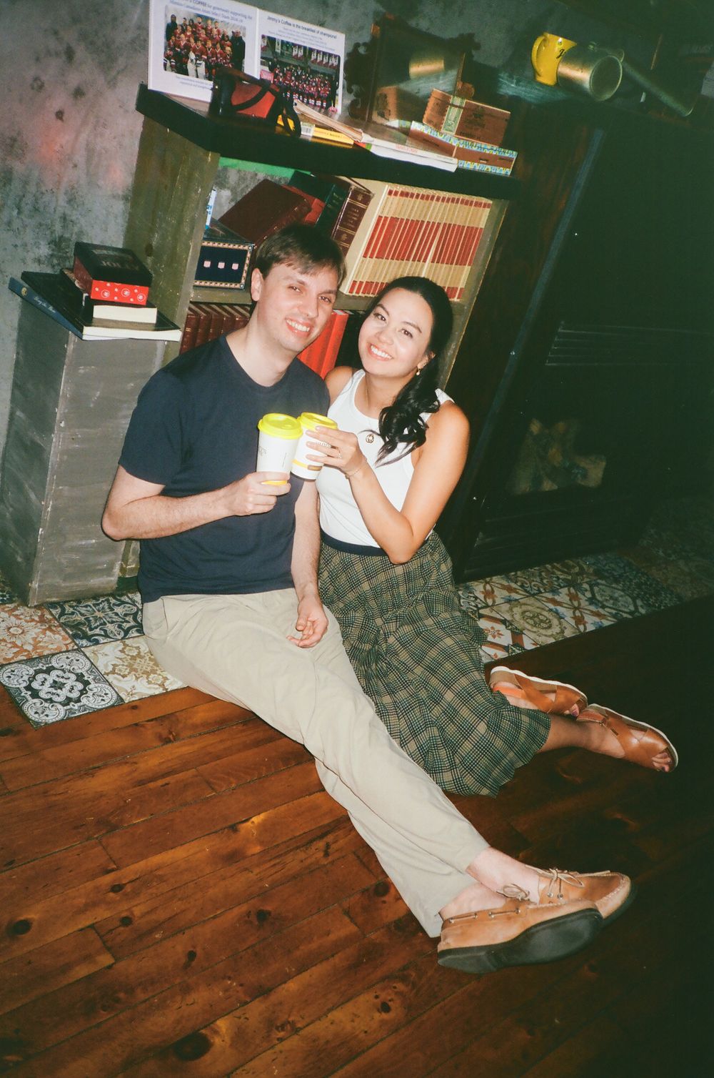 Casual couple sitting together on wooden floor in relaxed indoor setting.