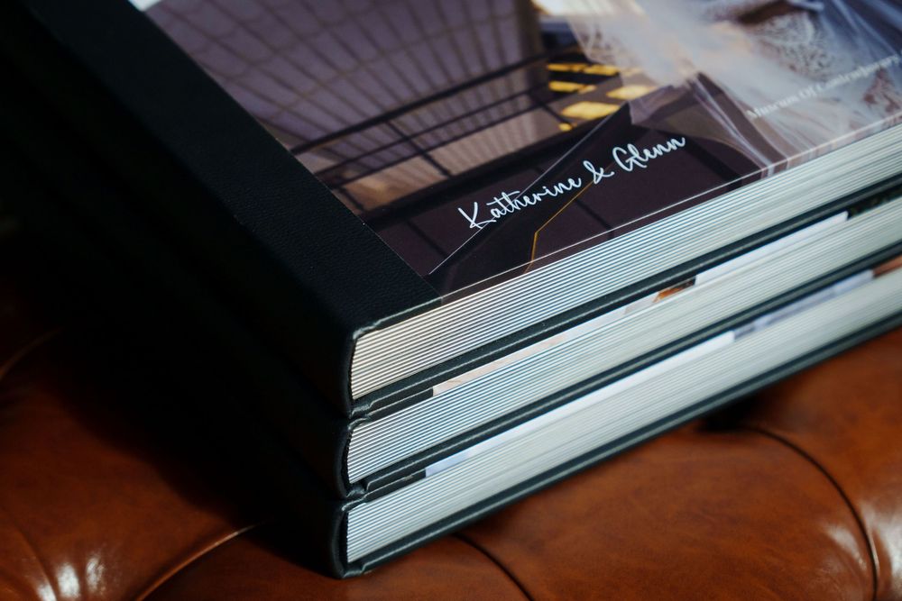 Stack of black hardcover books laid out in a row on dark wooden surface shown in dramatic lighting.
