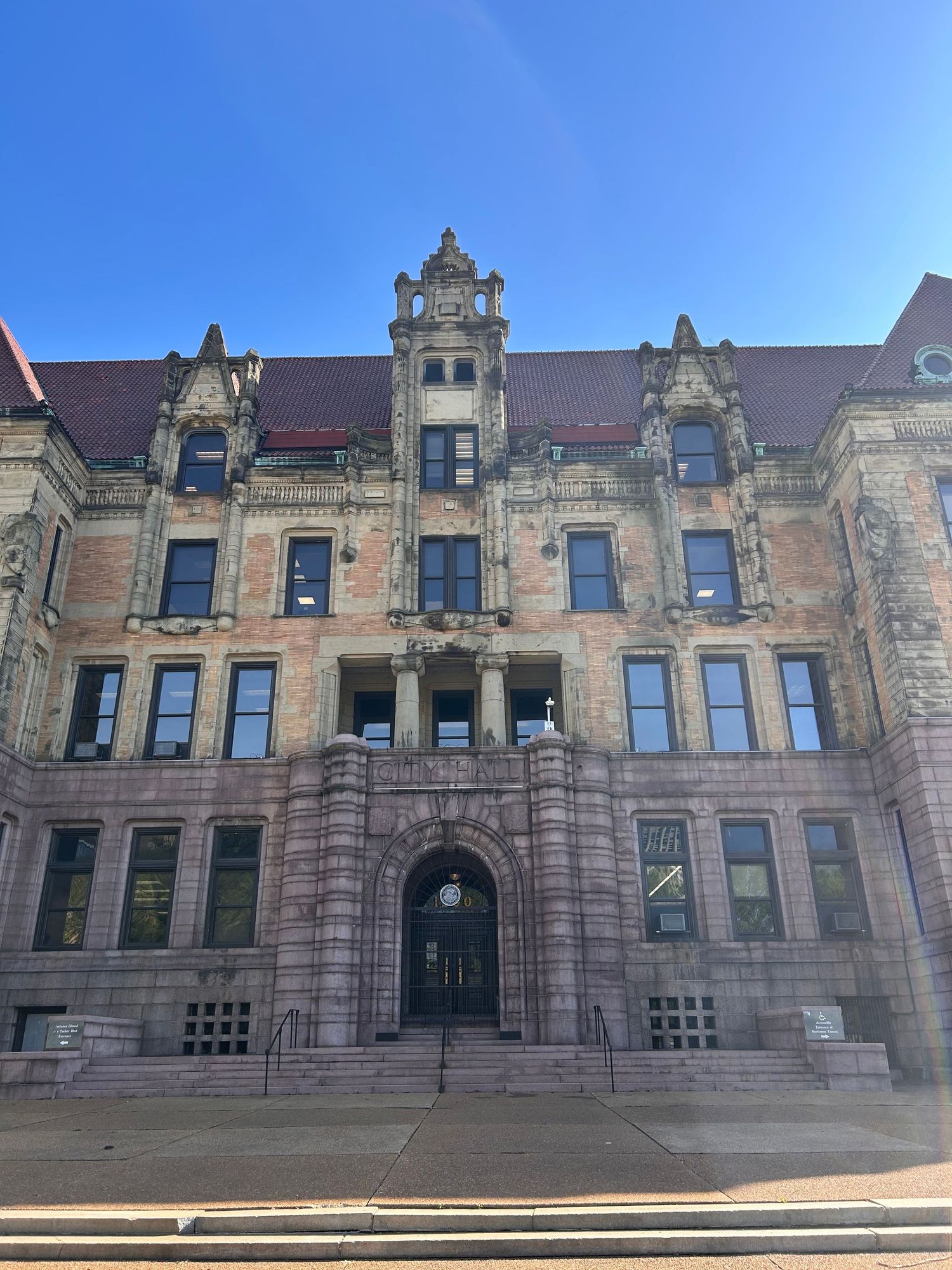 Ornate Victorian-style stone building with decorative turrets and symmetrical windows against a bright blue sky.