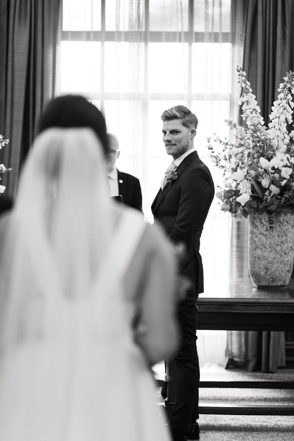 Black and white wedding photo of couple sharing first look moment in venue.