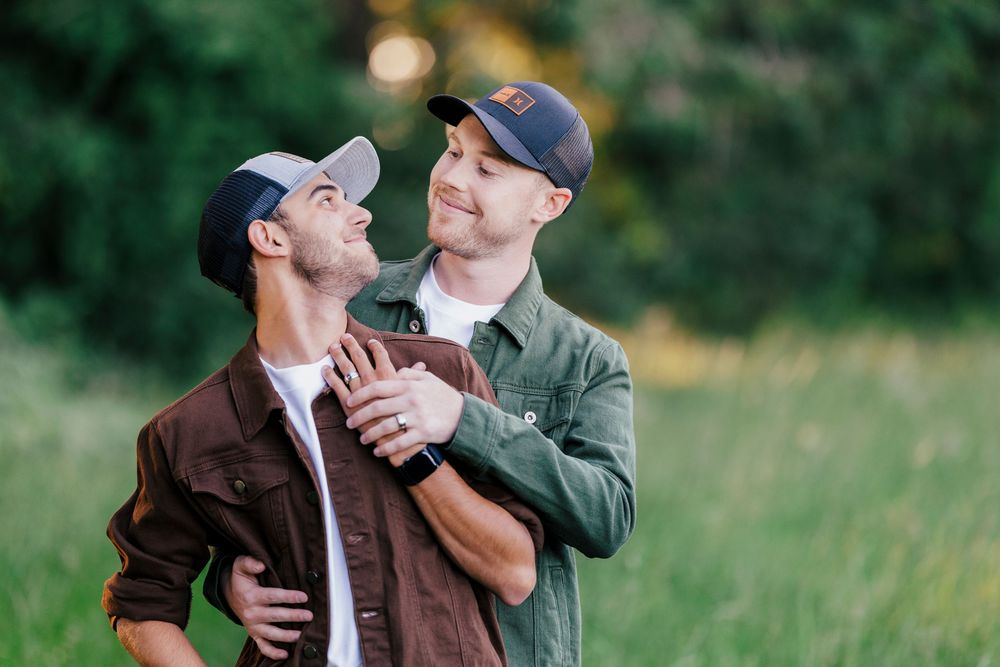 Two people share a tender romantic moment while dancing together outdoors in casual attire.