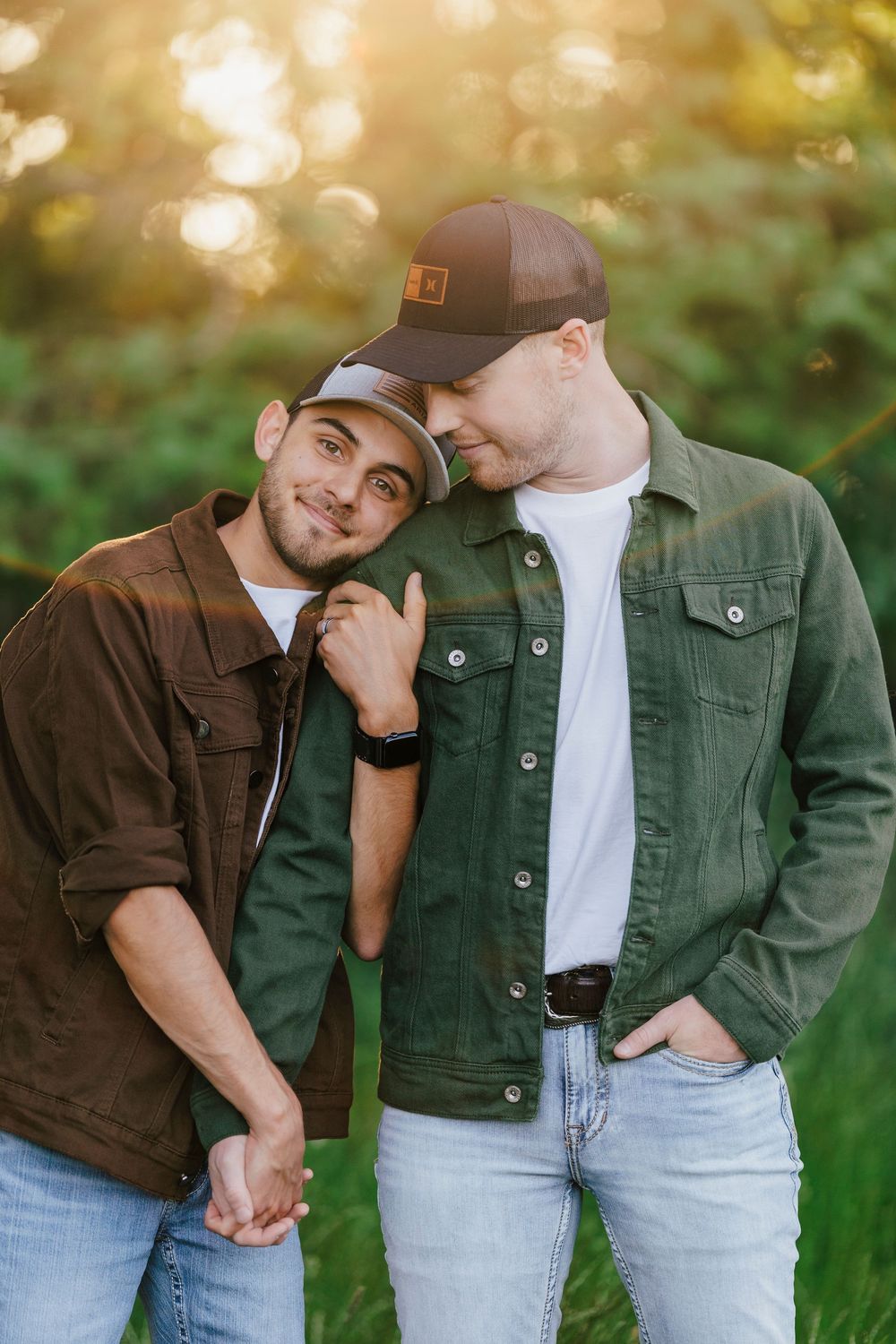 Two people in casual denim and jackets sharing an intimate moment outdoors at golden hour.