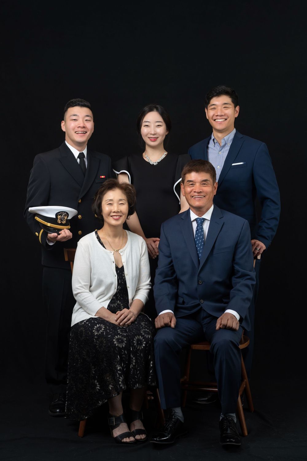 Professional family portrait against dark background with one member in military uniform.