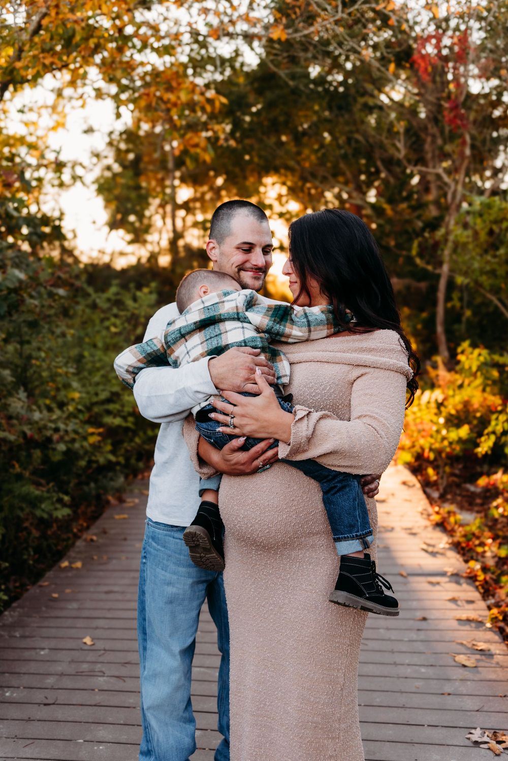 A heartwarming family scene on an autumn boardwalk with golden sunlight filtering through the trees.
