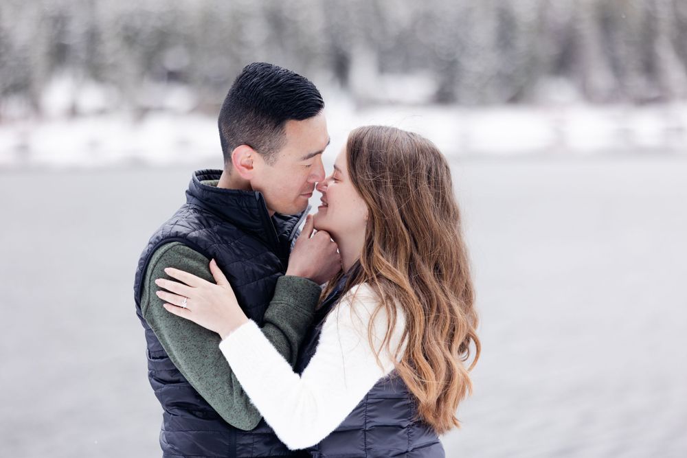 A romantic couple shares an intimate moment together against a snowy winter landscape.
