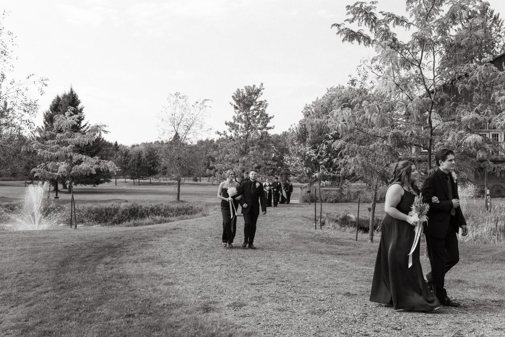 A vintage black and white photograph shows people strolling through a tranquil park setting with trees and pathways.