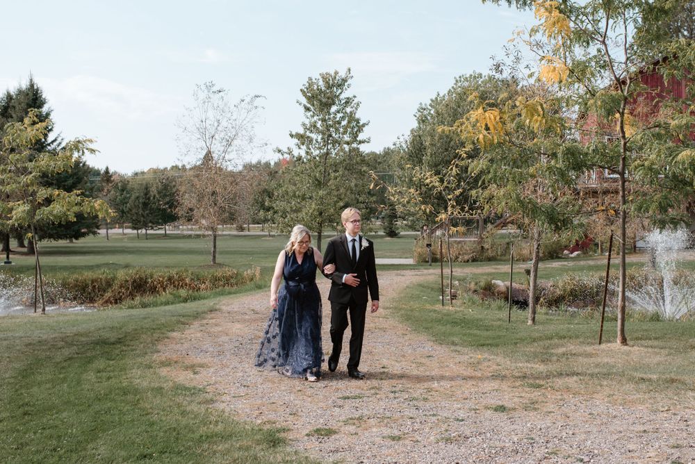 Two guests walk together on a gravel path through a scenic autumn park with colorful fall foliage.