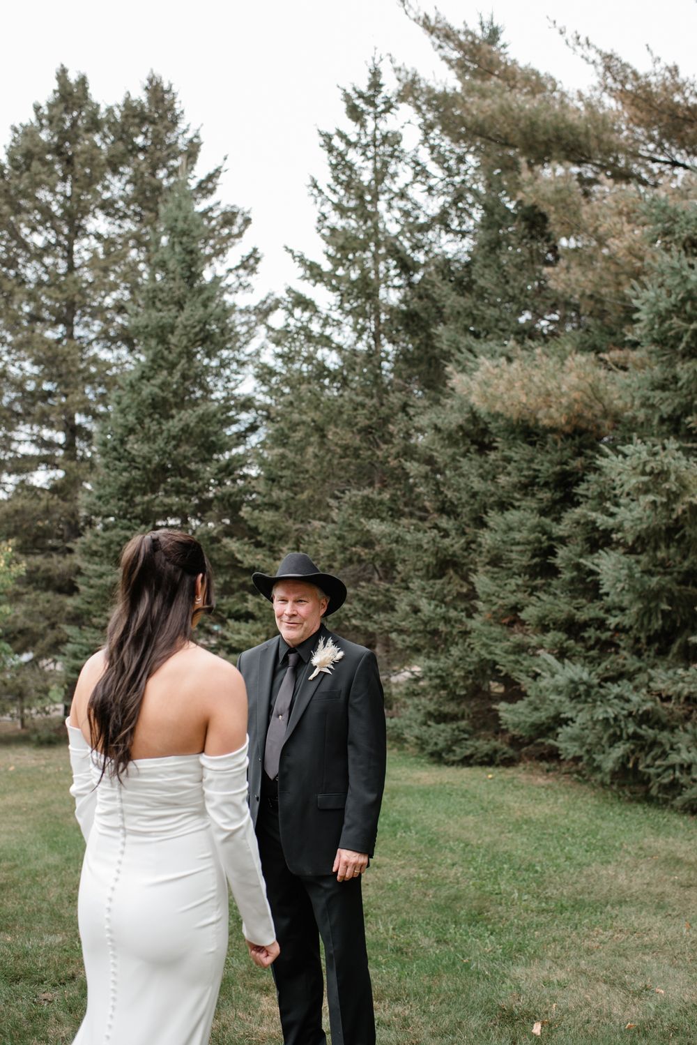 An intimate outdoor wedding scene with towering evergreen trees creating a natural forest backdrop.
