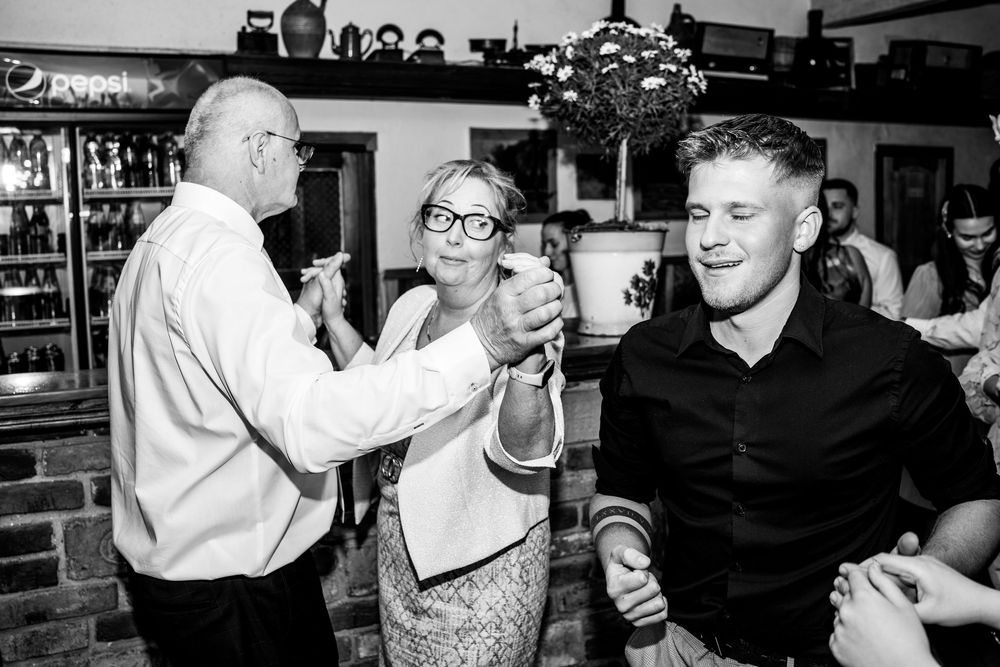 Party guests laugh and interact while enjoying drinks at a casual black and white bar scene.
