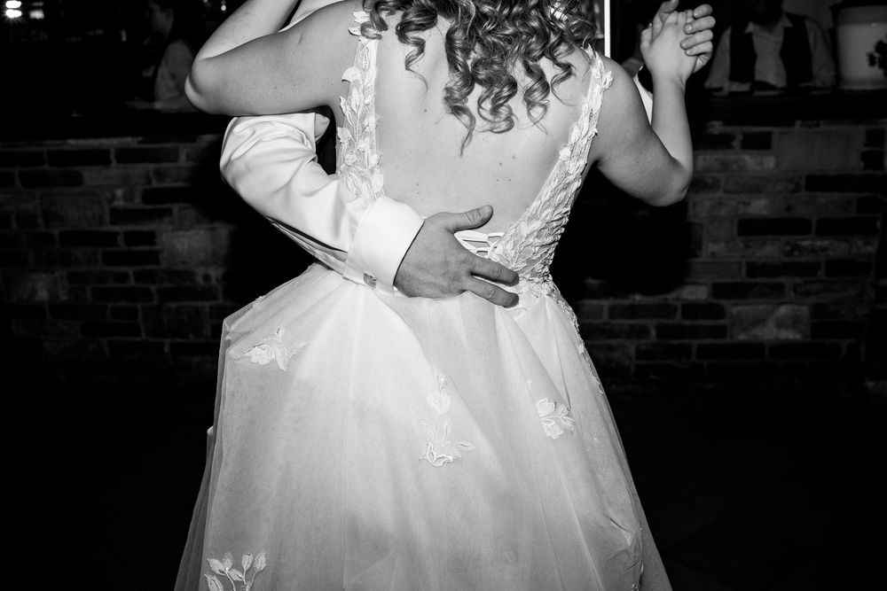 A couple dances close together during a wedding reception, with the bride wearing an elegant white lace gown.