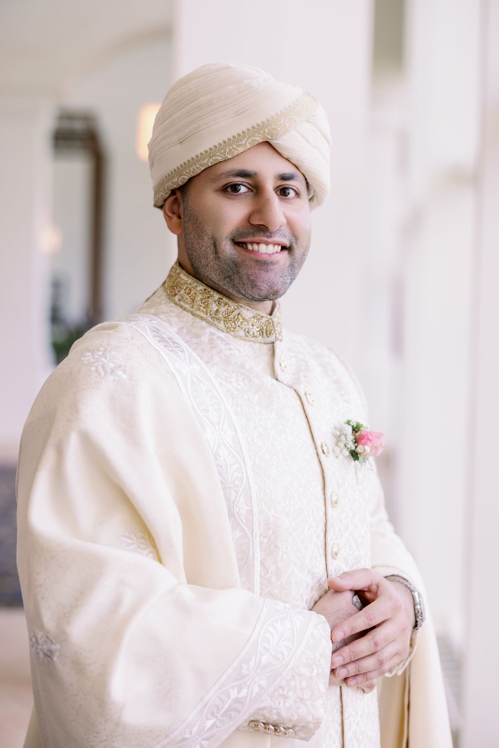 Groom in cream sherwani and traditional turban with gold embroidery details.