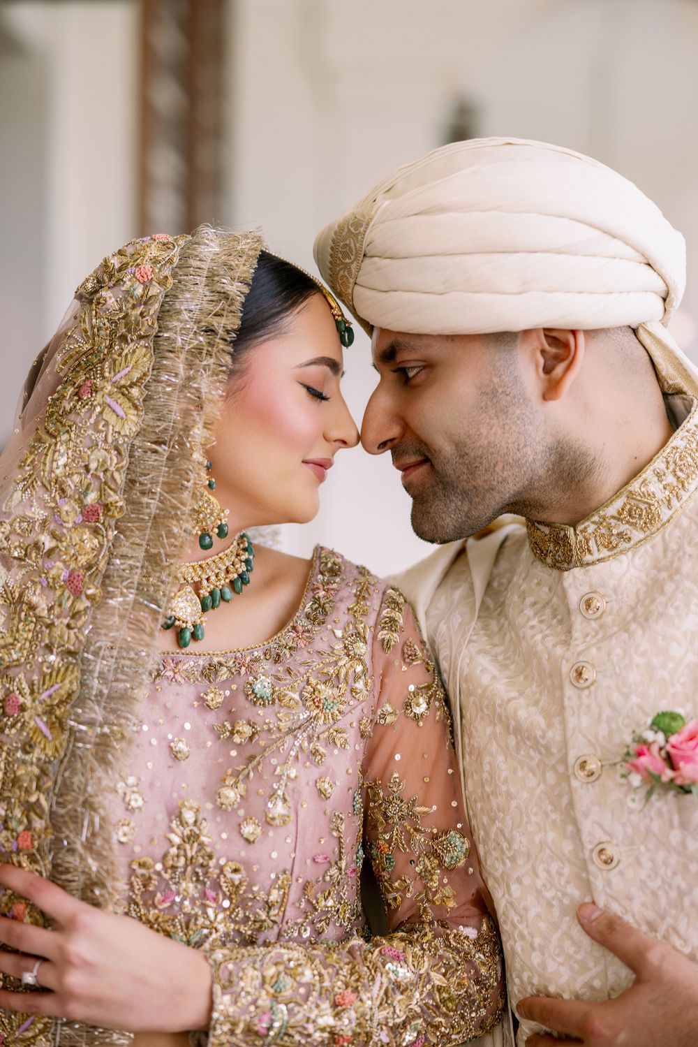 Intimate moment captured between couple in traditional South Asian wedding attire with detailed embroidery.