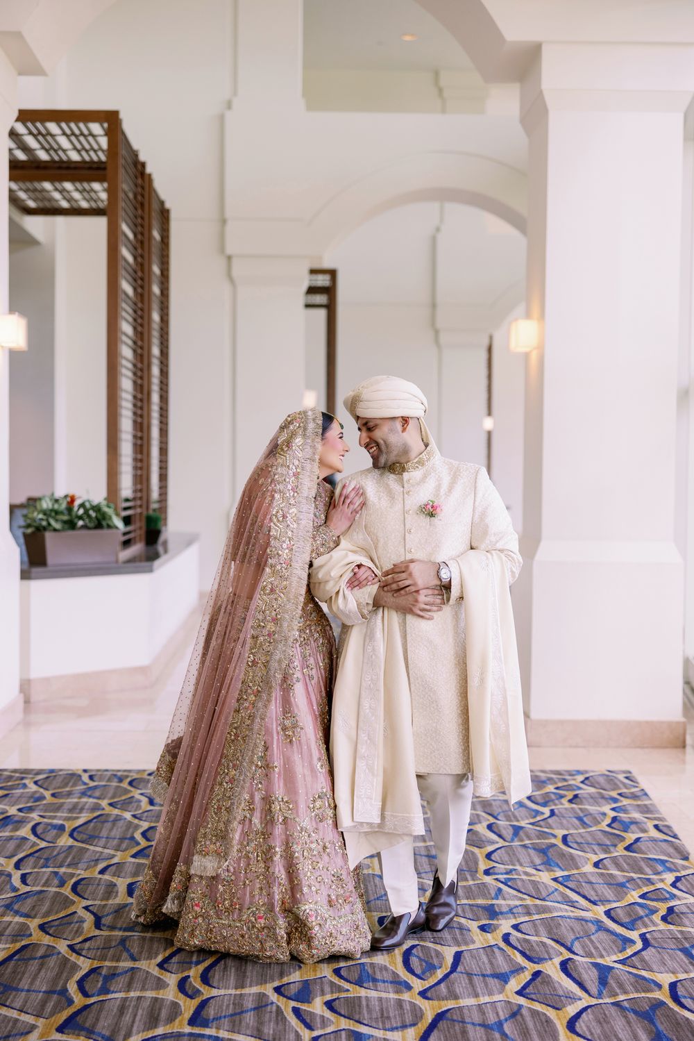 Couple shares an intimate moment in traditional wedding attire on decorative tiled floor.