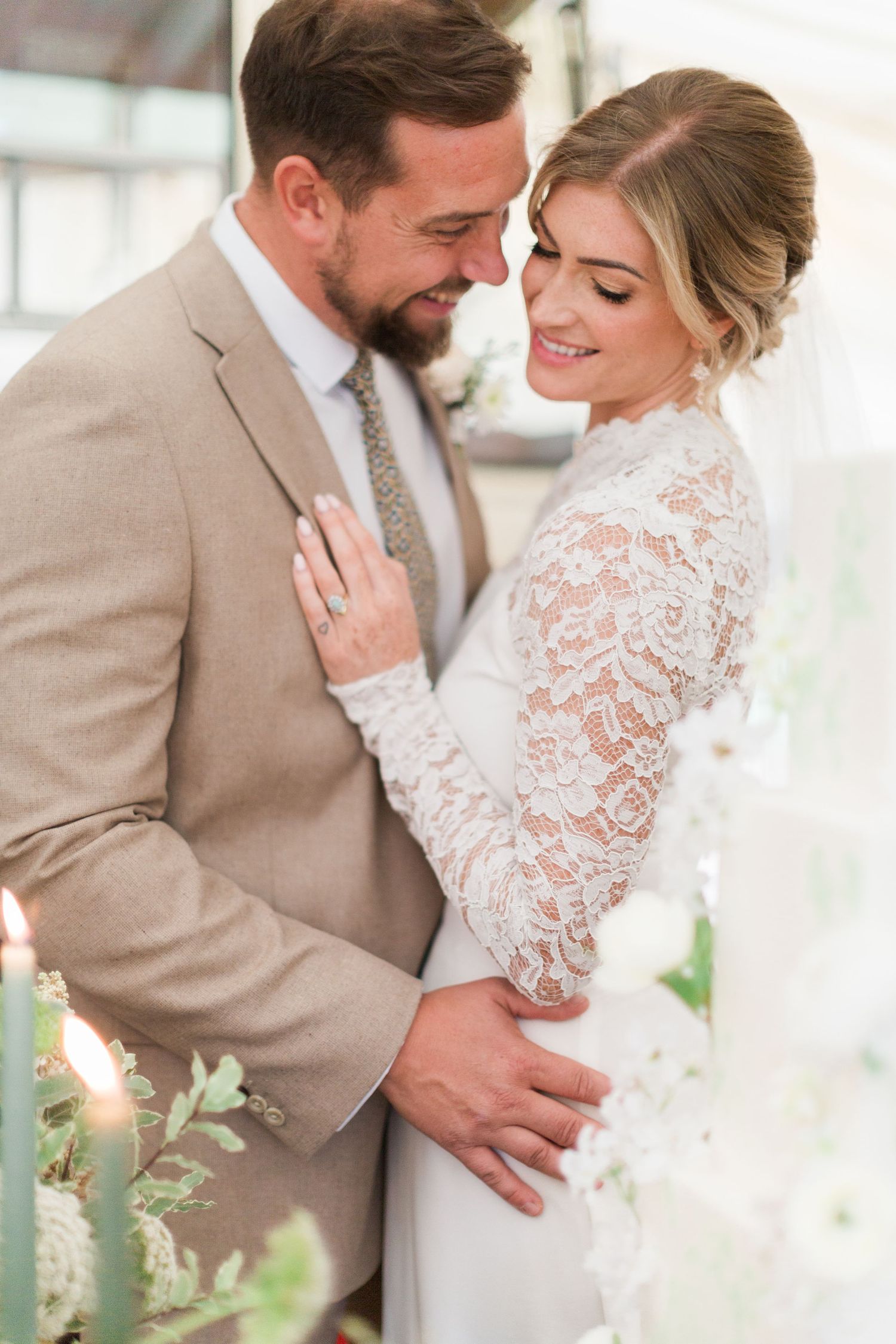 Wedding couple embrace intimately in elegant wedding attire with bride in lace sleeves and groom in mocha suit midlands Hayley Elizabeth