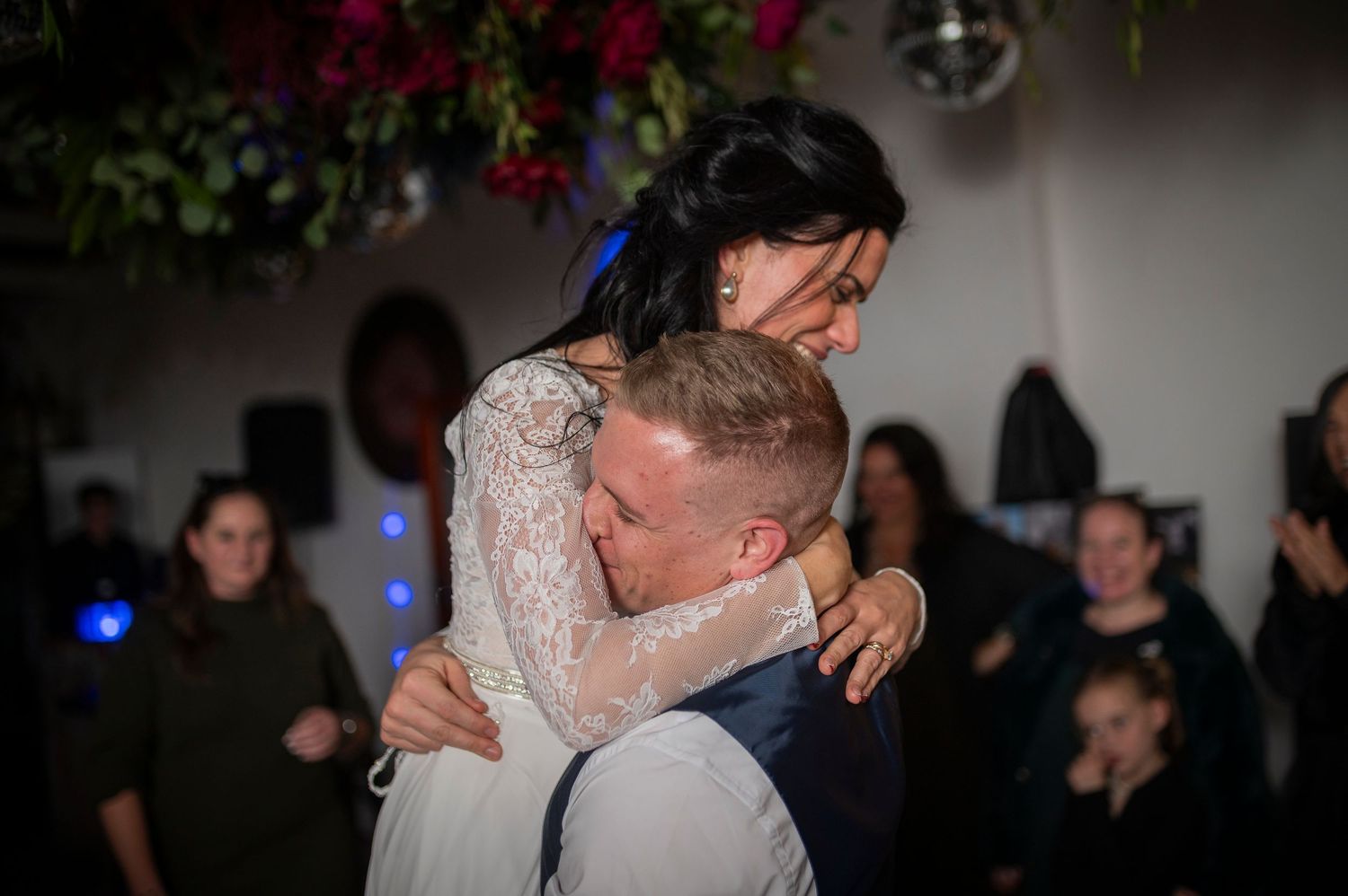 Couple dancing together on a dimly lit dance floor during what appears to be a wedding celebration.