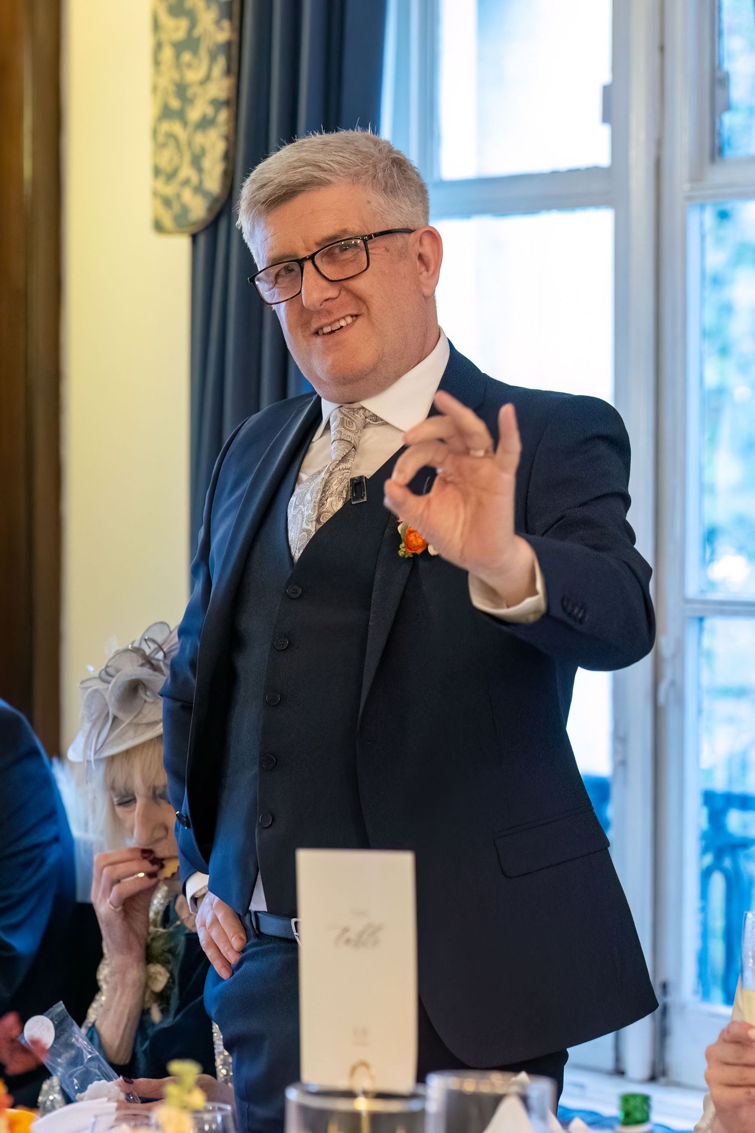 groom makes the perfect sign during his wedding speech at the Athenaeum Liverpool. Stuart Morris Photography Liverpool wedding photographer.