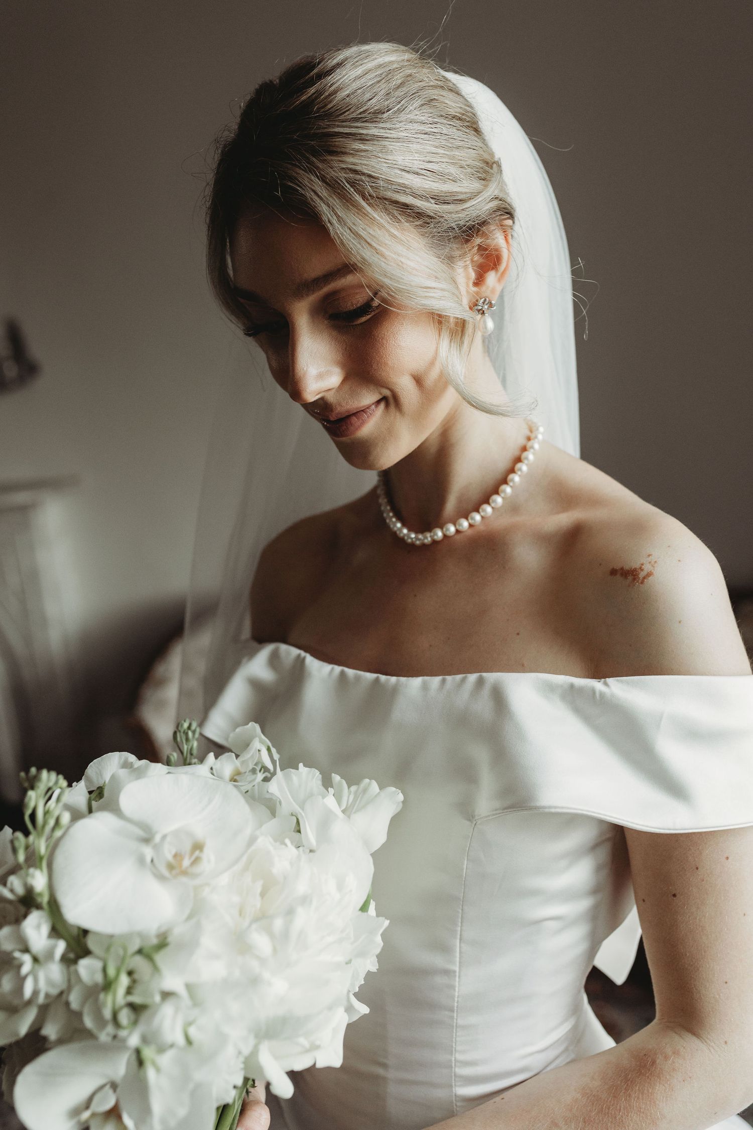 A classic bridal portrait series in soft lighting shows elegant wedding attire with white flowers and pearl accessories.