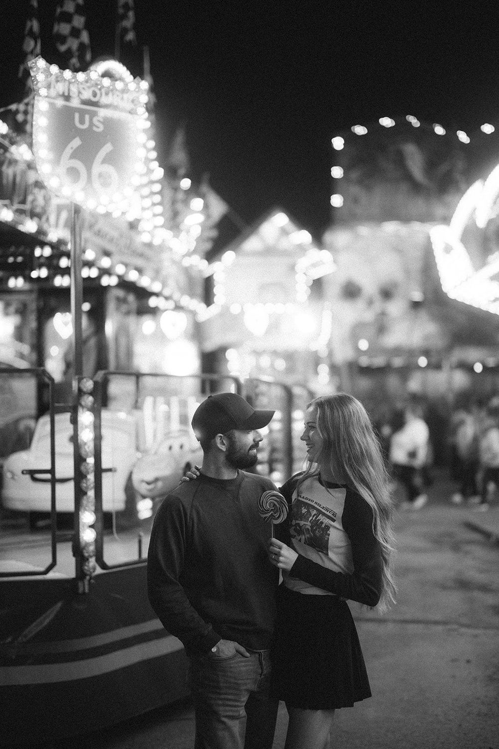 A romantic couple sharing a moment at Hull Fair with Route 66 neon lights glowing in the background. Captured by Lincolnshire photographers.