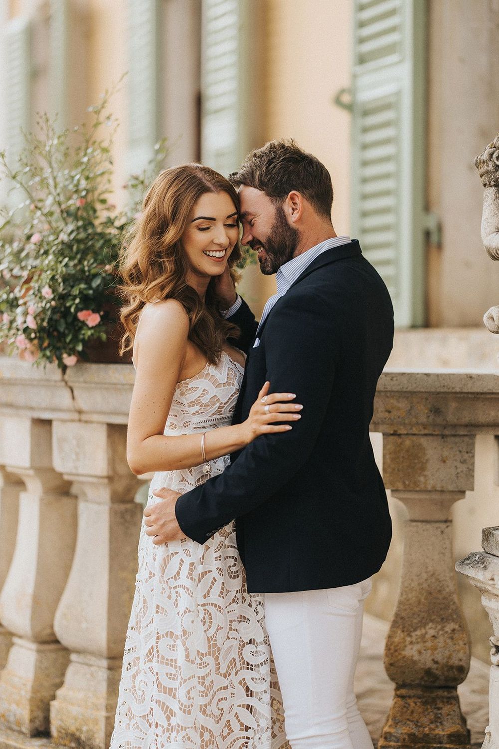 Romantic moment captured between couple in formal attire against elegant Italian building columns and shutters.