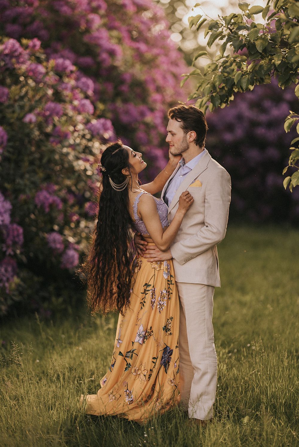 A romantic dance sequence on grass with pink flowering trees in the background showing a couple in yellow dress and white suit.