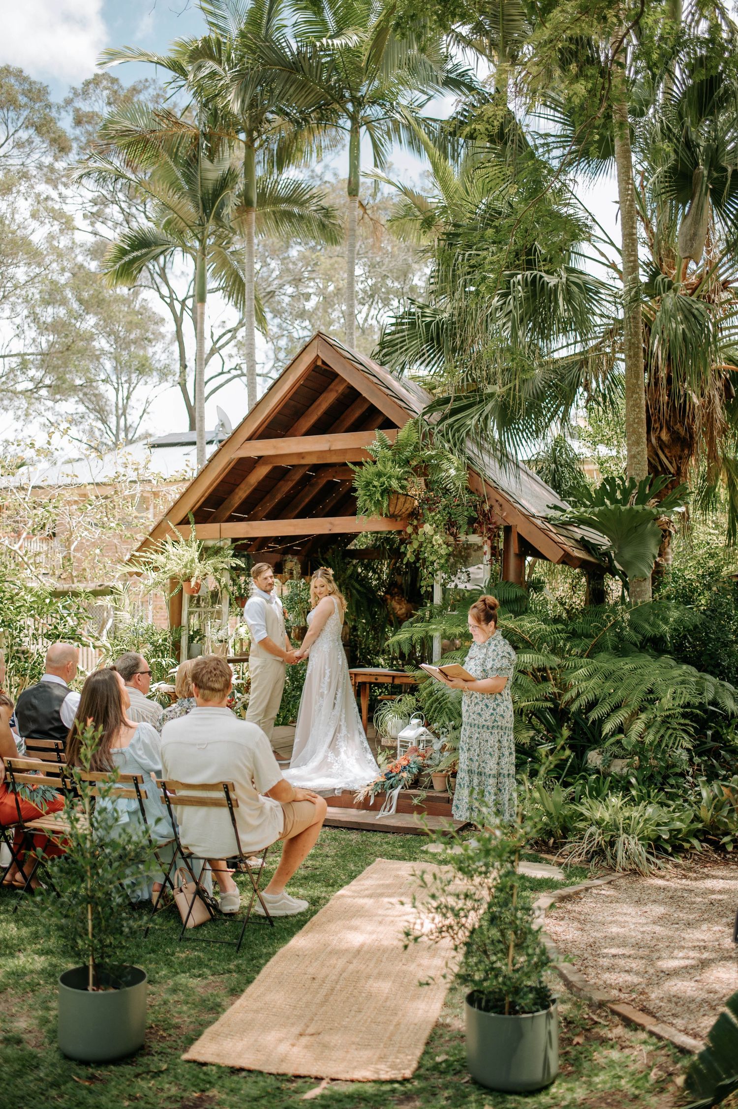 A couple shares a sweet moment while cutting their wedding cake together under a crystal chandelier and rustic wooden beams.