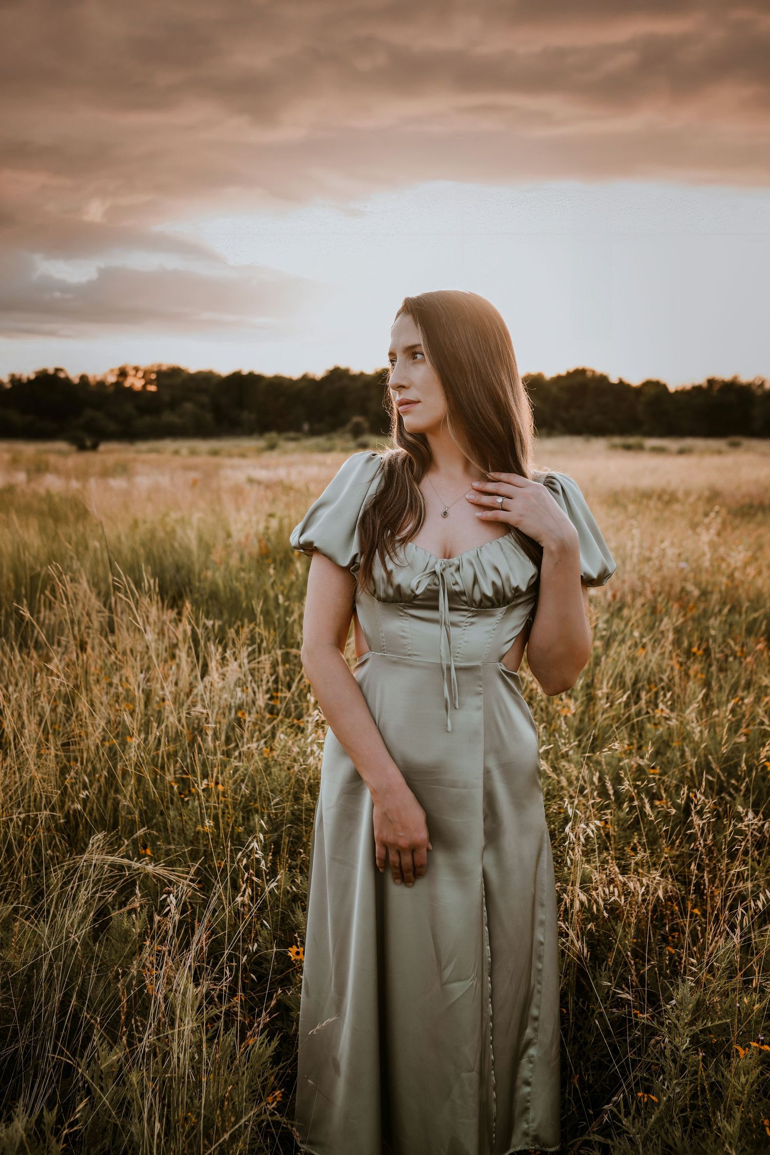 Bride-to-be standing alone in tall golden grass at sunset