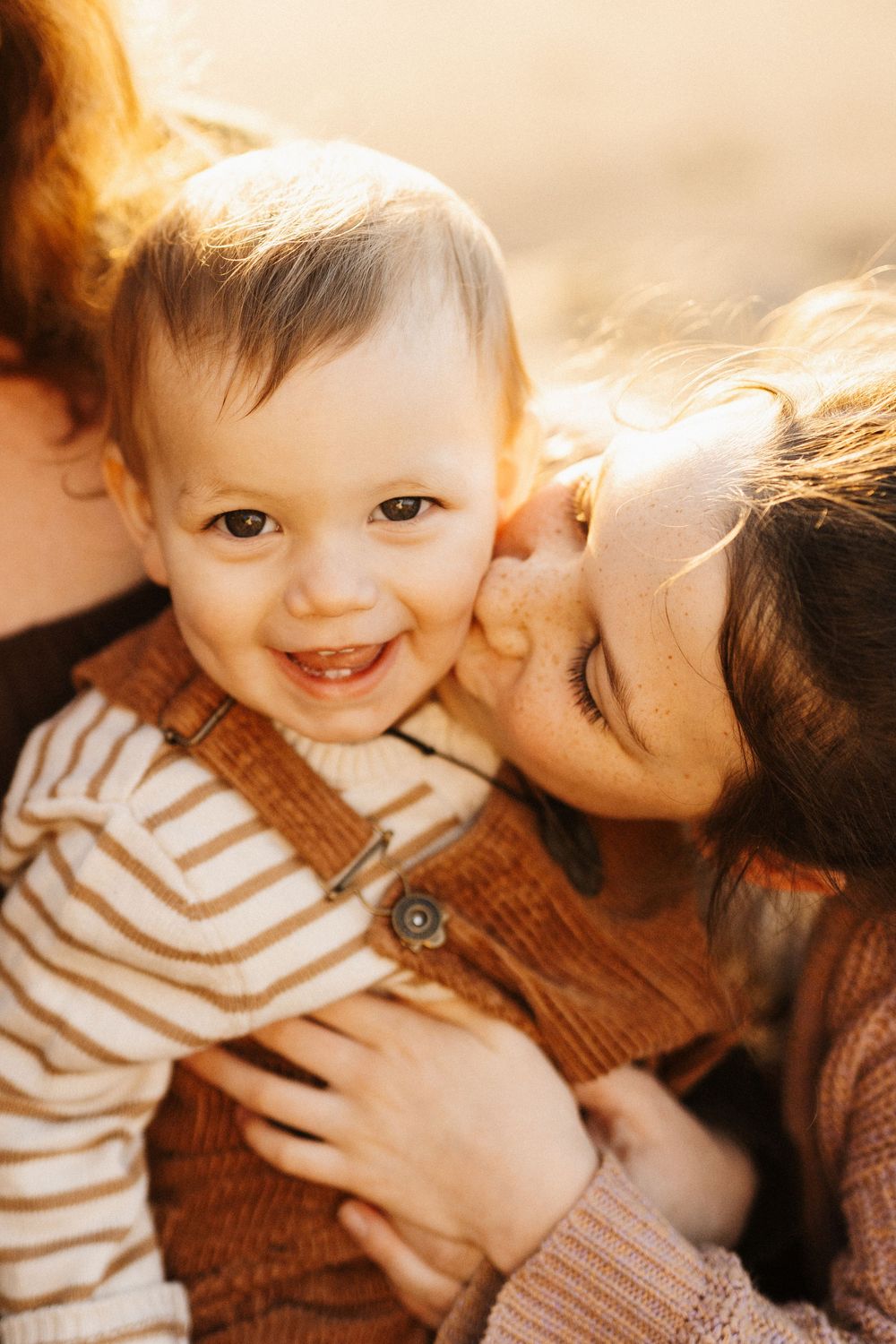 A warm and tender moment captured in golden light showing affection and closeness between loved ones in brown and white attire.