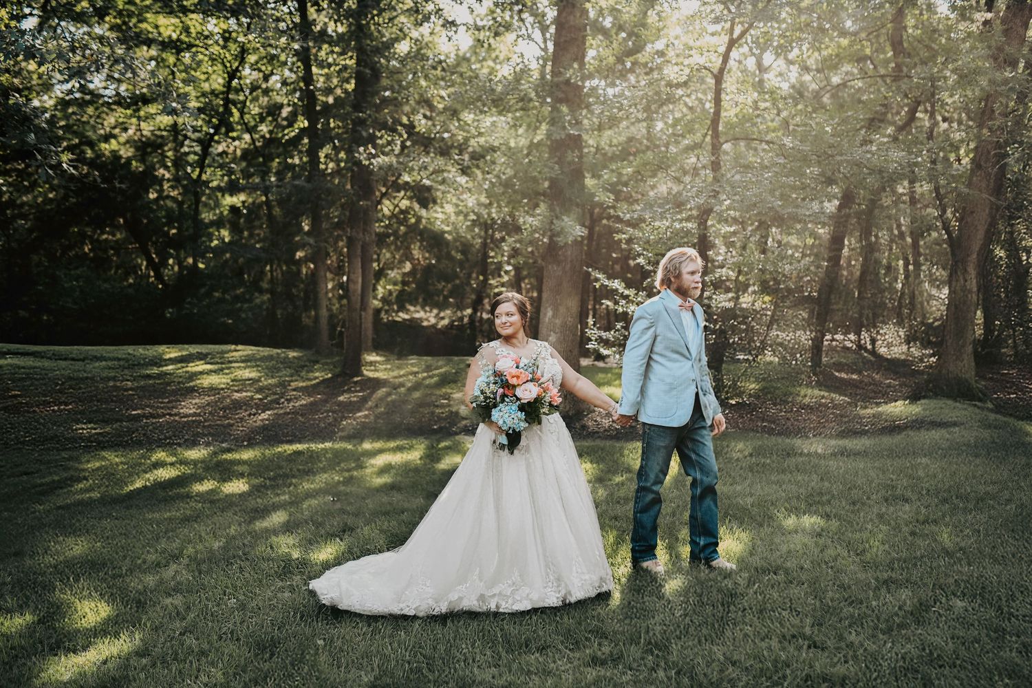 Candid moment of laughter as couple walks through sunlit trees at dusk