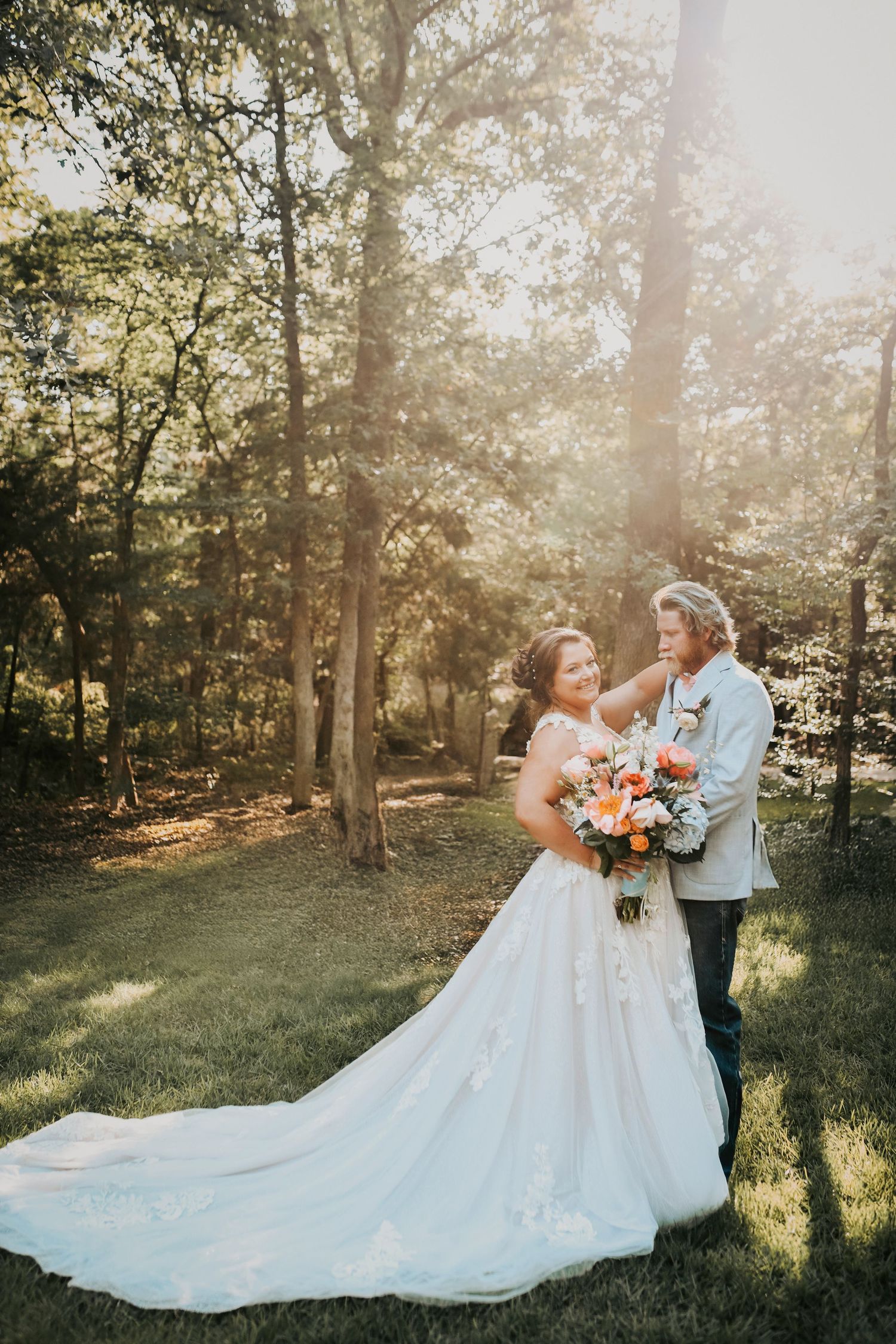 Glowing sunset behind bride and groom beneath golden-lit trees