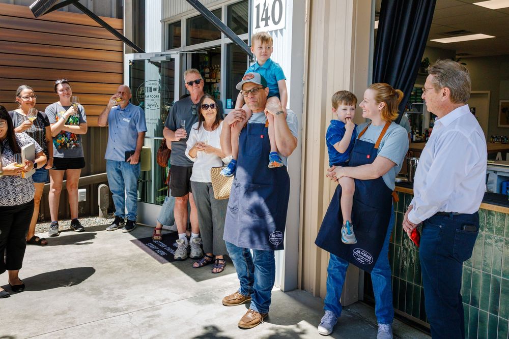 A diverse group of people standing outside a retail storefront entrance waiting in line.