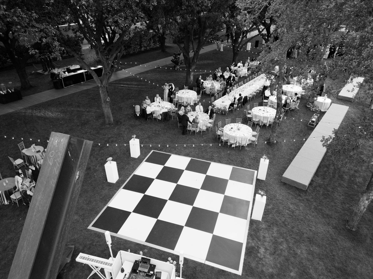 Aerial view of an outdoor event with tables and a large checkerboard pattern on the ground.