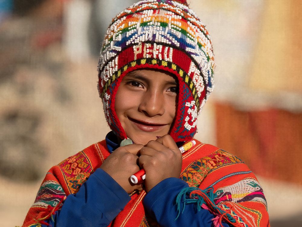Traditional Peruvian handmade knit hat and colorful clothing in vibrant red and blue colors.