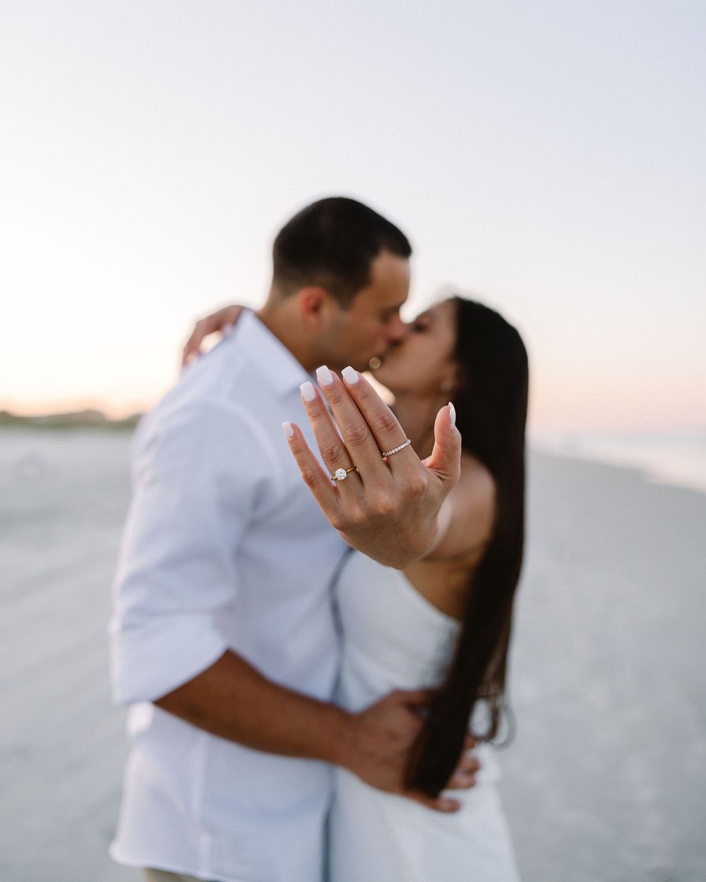 A romantic beach engagement moment showing off a new ring at sunset.