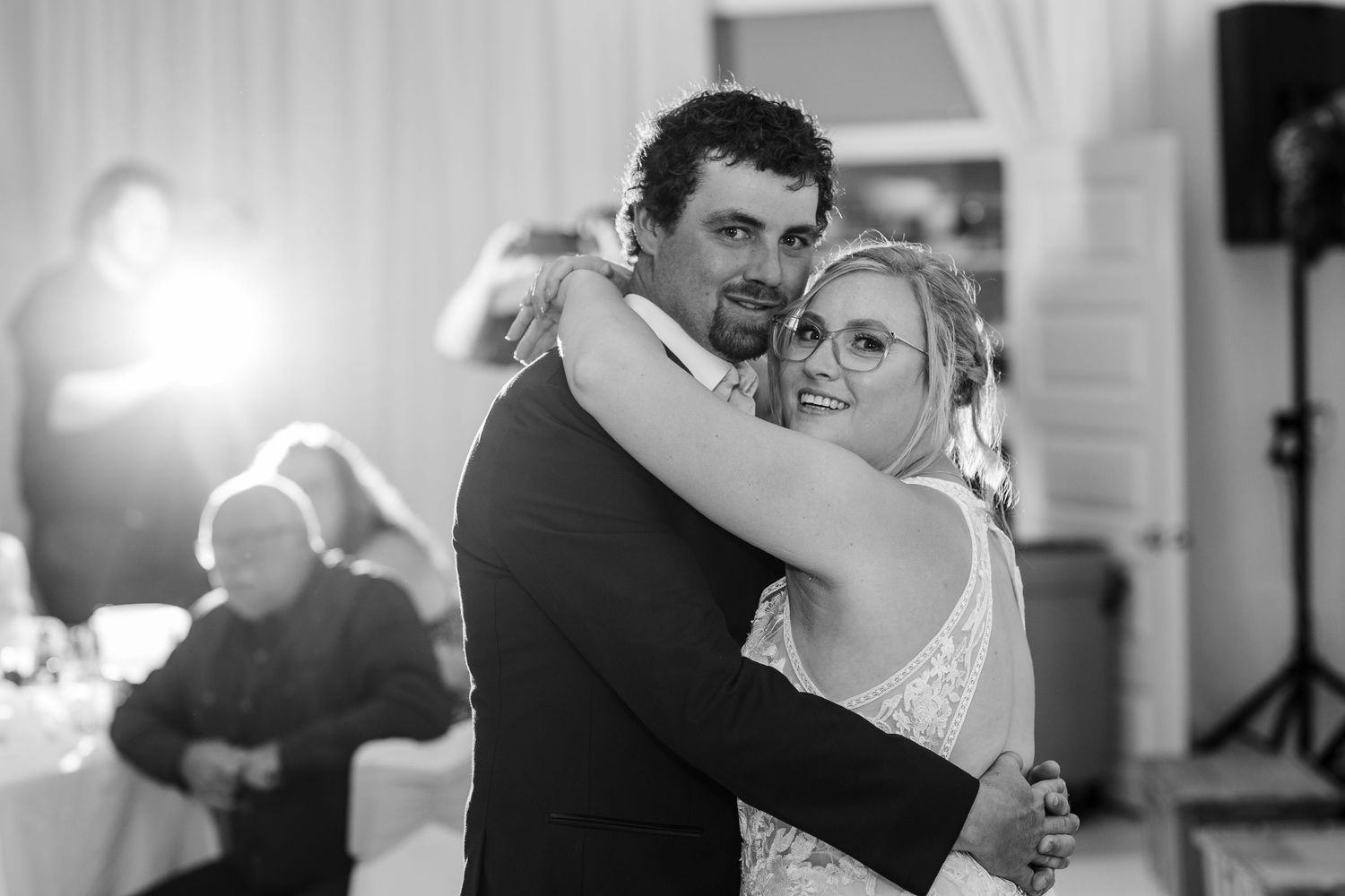 A tender black and white photo of a couple dancing together at their wedding reception.