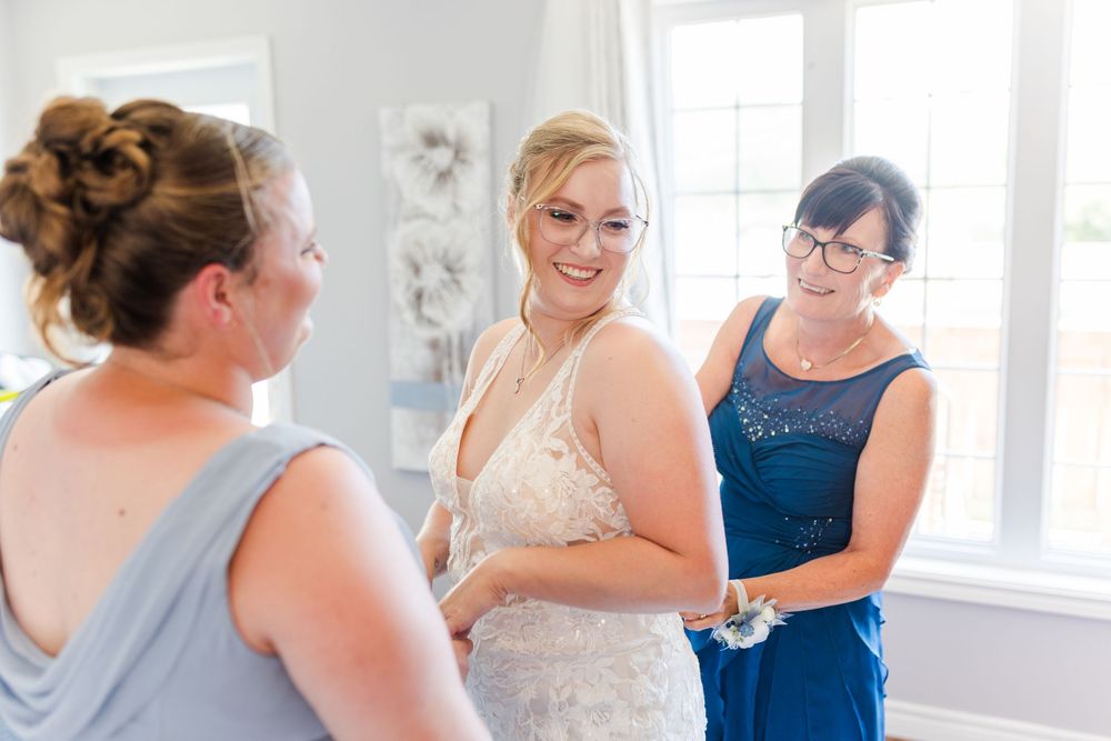 Wedding preparations underway with people getting ready in a bright white room.