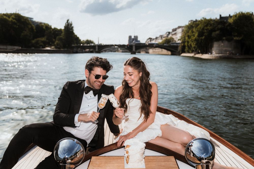 Newlyweds enjoy a romantic boat ride along a scenic river in Paris.