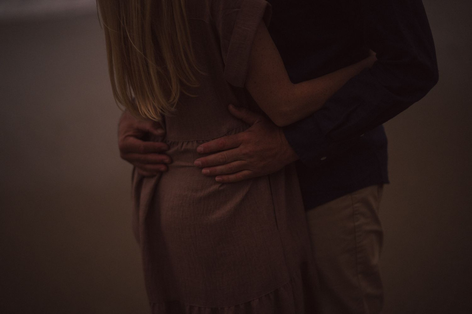 A romantic couple sharing an intimate dance moment together in dramatic lighting.