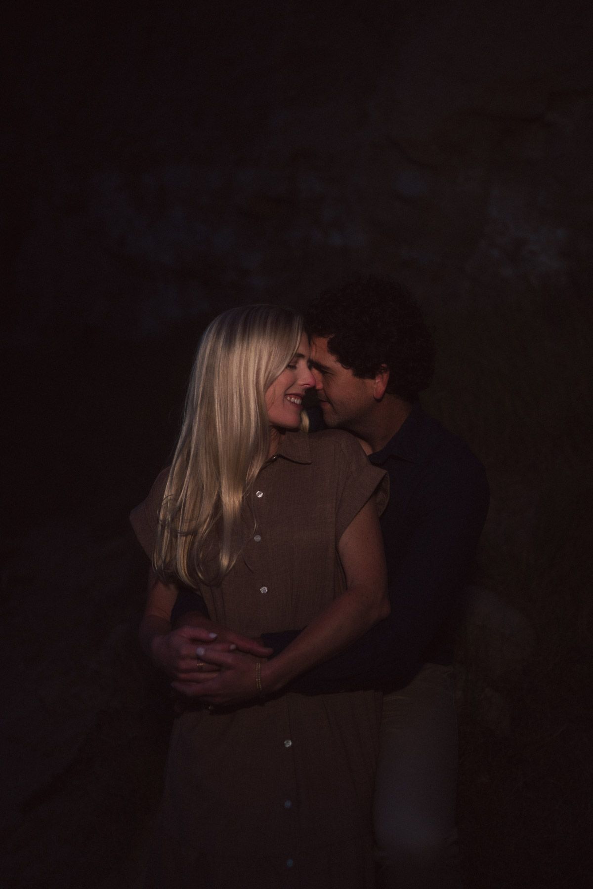 A silhouetted couple sharing an intimate embrace in a dimly lit setting.