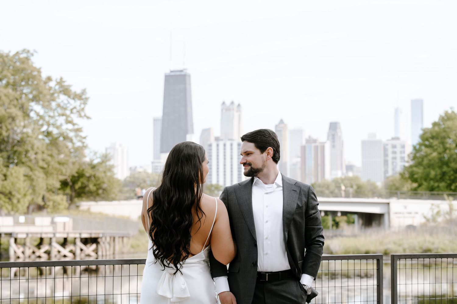 A couple stands at the Chicago lakefront promenade with Willis Tower and city skyline in golden light.