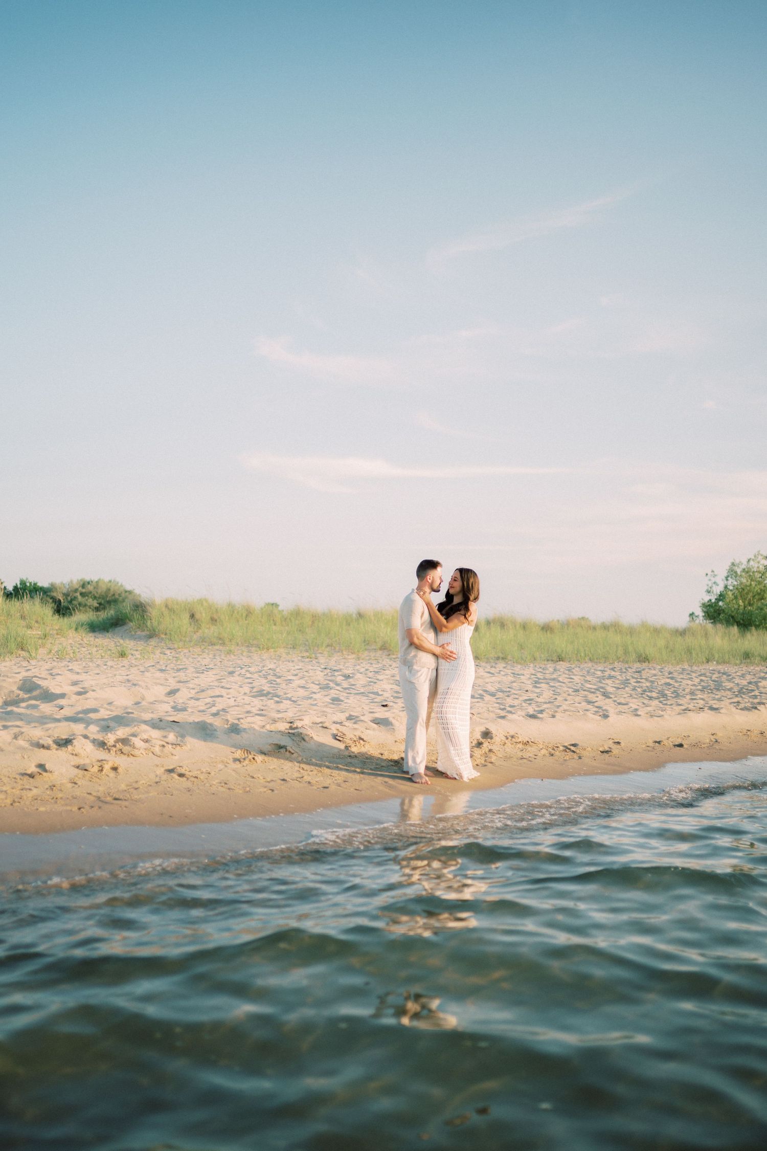 Romantic seaside photoshoot sequence showing couple walking into ocean water at dusk.