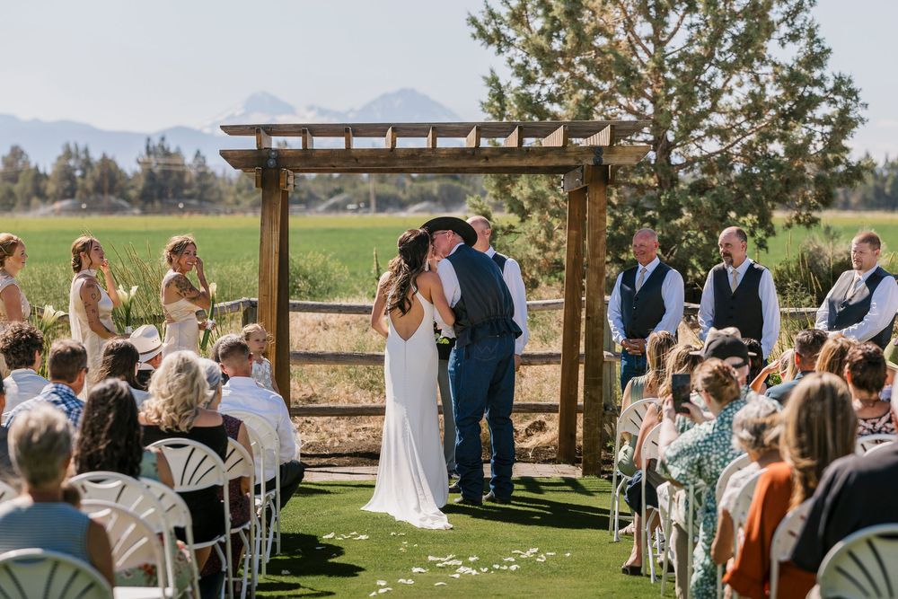 Outdoor wedding ceremony on a golf course with mountain views and wooden pergola during a sunny afternoon.