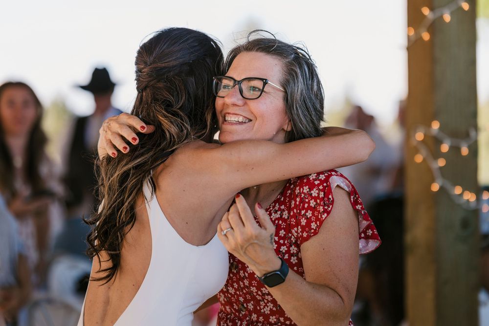 Two people share a joyful embrace at a party decorated with twinkle lights.