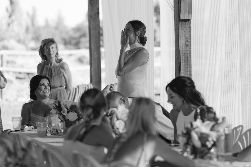 A group of people gathered for a dining event at what appears to be a covered outdoor venue in black and white photography.