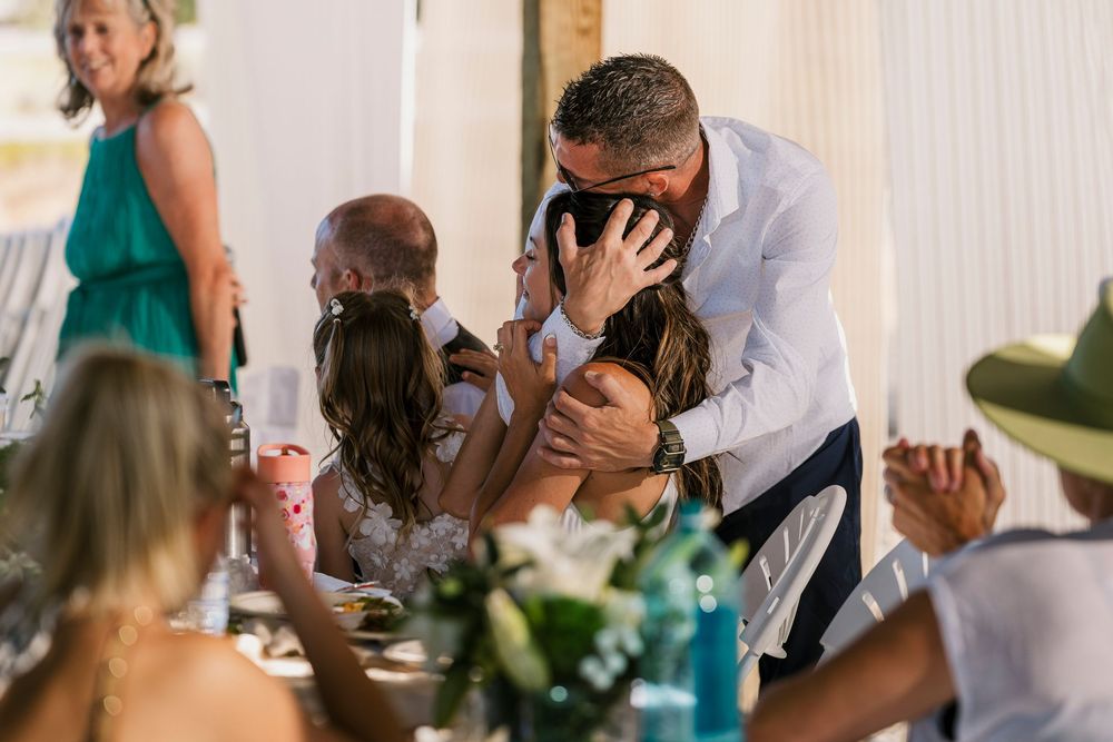 An emotional embrace shared between people during a special moment at an elegant reception dinner with table settings and decor.